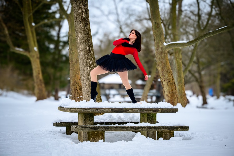 Dance portrait in a red top and black tutu on a snow-covered picnic table